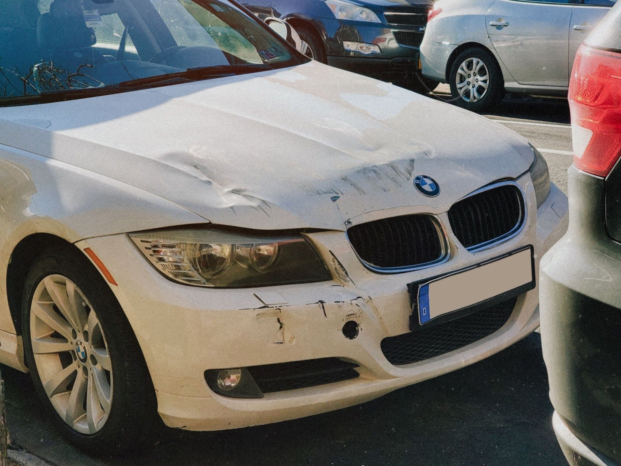 The crumpled hood and bumper of a white car after a collision