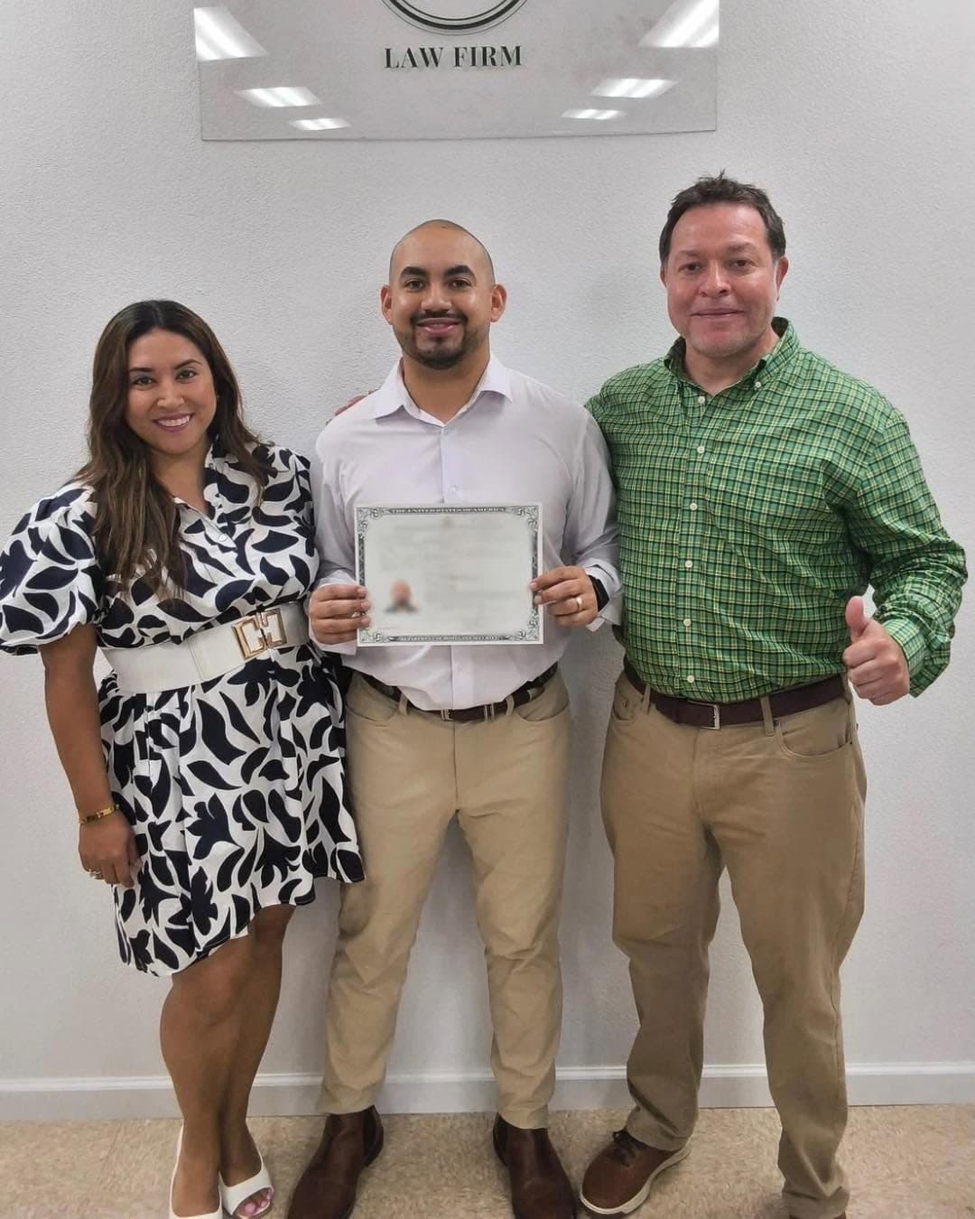 A client holding a naturalization certificate with attorney Luis Vasquez