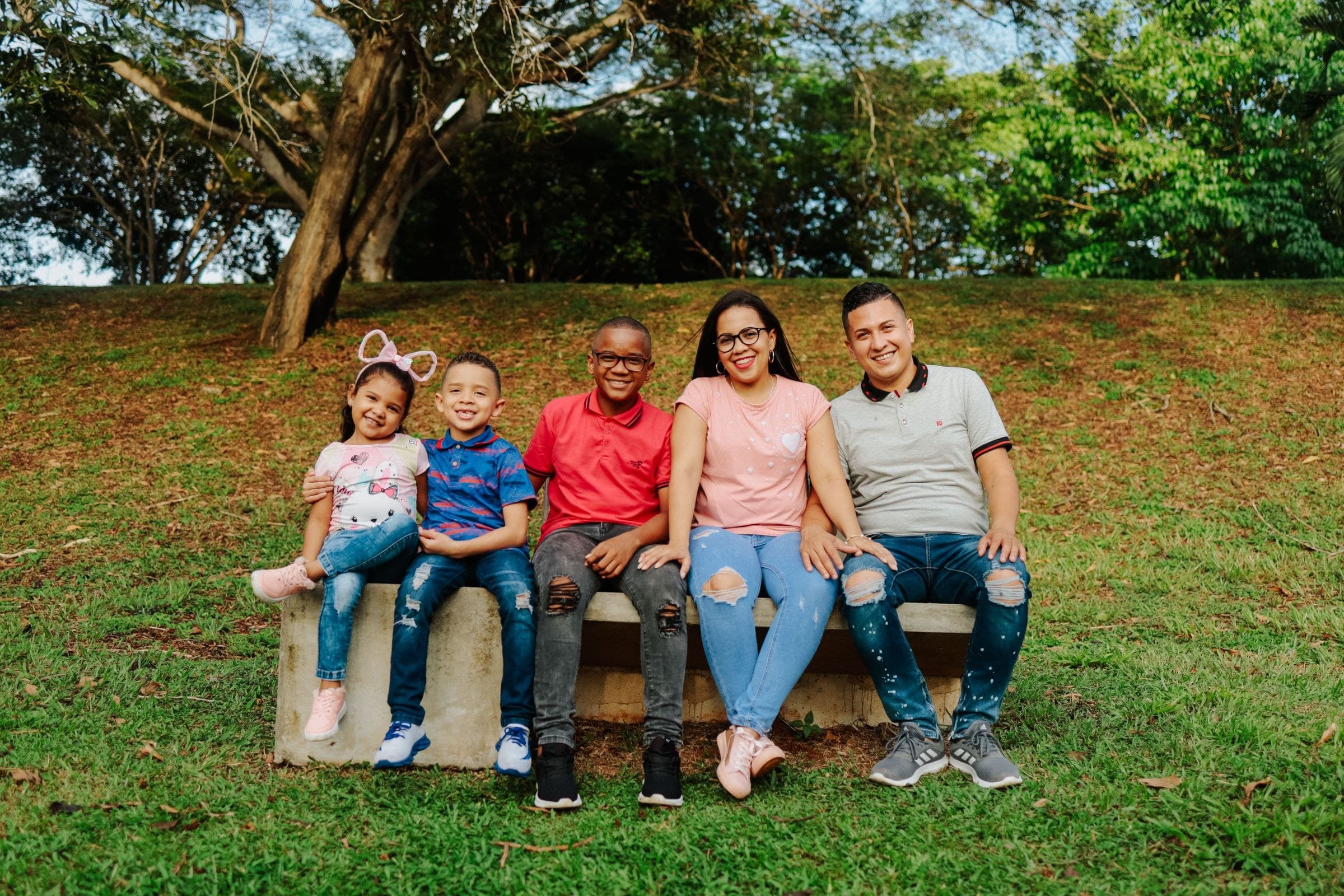 A family of five sitting together on a park bench